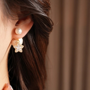 Detail of 18K gold plated earring with pearl stud and rhinestone star charm on model
