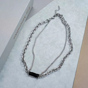 Detail of layered silver chain necklace featuring a rectangular black zircon pendant