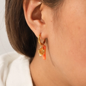 Detail of stainless steel gold hoop earring with flower and pearl charms on model