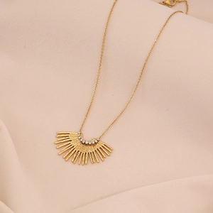 Gros plan du collier pendentif soleil doré serti de cristaux sur tissu beige