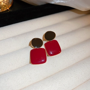 Detailed view of vintage enamel geometric earrings in deep red and black on a tray