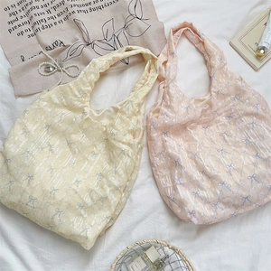 Vue détaillée des sacs fourre-tout jaune et rose à imprimé nœud sur du lin blanc pur