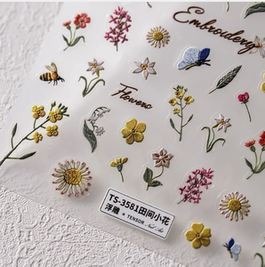 Macro detail of 5D embossed nail stickers featuring daisy and bee patterns