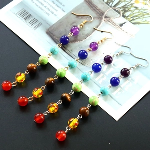 Detail of seven chakra stone bead drop earrings with boho tassels on a glossy magazine