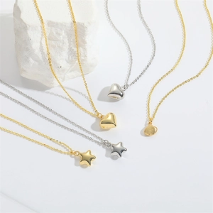 Minimalist gold and silver necklaces with heart and star pendants on white stone