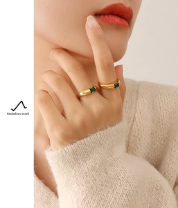 Detail of two 18K gold plated stainless steel rings with square green zircon on a model
