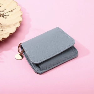 Blue litchi grain leather wallet with metal ring and round pendant on pink background