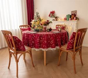 Close-up of red Christmas tablecloth with golden deer patterns and festive fringe details