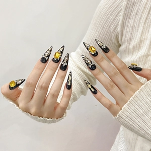 Luxury black stiletto press-on nails with yellow zircon stones and gold foil accents