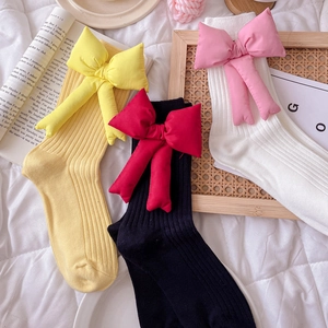 Three pairs of cotton slouch socks in yellow, black, and white with large stuffed bows