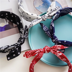 Flat lay of four paisley pattern knotted headbands in black, white, navy, and red fabric