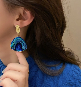 Close-up of fan-shaped blue-green gradient earrings with golden hammered metal texture