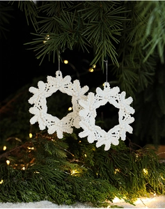 Close-up of white snowflake ornaments with snow-like texture on green pine branches