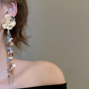 Close-up of bohemian floral earrings with long metallic tassels and colorful beads