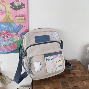 Détail du sac bandoulière en toile crème avec bordure bleue et broderie de lapin mignon