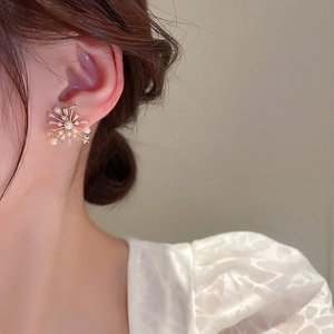 Détail de boucles d'oreilles fleurs plaquées or avec perles et zircons brillants