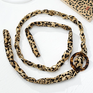 Detail of leopard print belt with golden chain wrap and tortoise shell round buckle