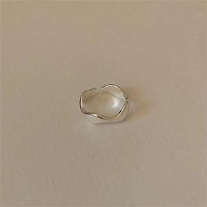 Macro shot of polished S925 sterling silver wavy open ring with mirrored irregular curves