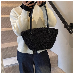 Détail du sac seau noir en fausse fourrure bouclée avec de fines bandoulières en cuir