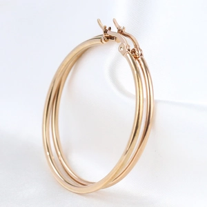 Detail of 50mm gold hoop earrings in polished stainless steel on silk background