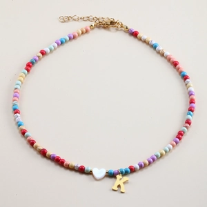 Detail of colorful beaded necklace with a white heart shell and golden letter K pendant