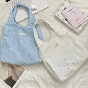 Detail of light blue and white sequined tote bags with vertical striped fabric texture