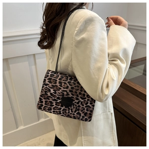 Gros plan du sac bandoulière léopard avec chaîne en métal noir et boucle en forme d'écu