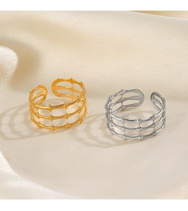 Close-up of gold and silver multi-layer hollowed-out rings on silk fabric background