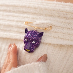 Vue détaillée d'une broche tête de panthère violette à pois roses sur tricot blanc