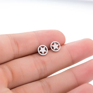 Detail view of silver hollow star stud earrings held by hand showing small size
