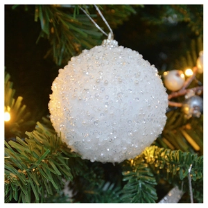 Close-up of white plush Christmas ball ornament with sequins on a decorated tree branch