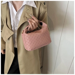 Close-up of pink woven handbag texture held by a model against a white wall background