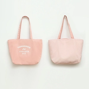 Detail of pink canvas tote bags featuring plain text print and vertical stripe pattern