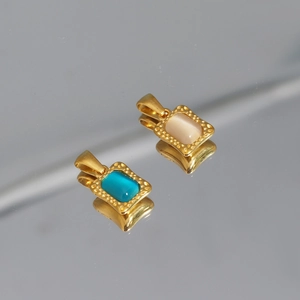 Macro shot of rectangular gold metal pendants with beige and blue cat eye stone inlays