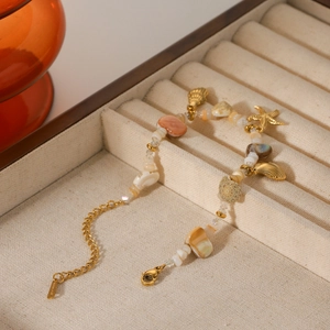 Golden ocean style bracelet with starfish seashell charms and natural beads on velvet tray