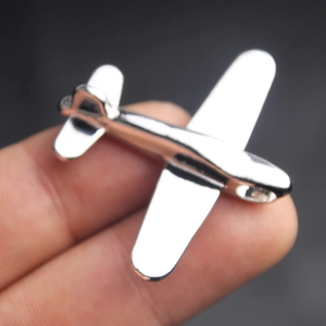 Detail view of a silver airplane pendant held by fingers to show product size and scale