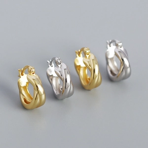 Detail of twisted hoop earrings in gold and silver finish with high polished metal texture