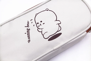 Close-up of a cream canvas pencil case featuring a brown running bear print and zipper