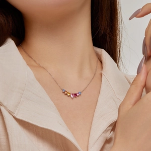 Close-up of multicolored heart-shaped zircon necklace on neck in refined silver chain