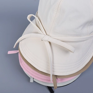 Bow tie sun hats in multiple colors stacked showing cotton canvas texture and sewing details