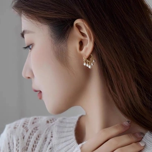 Close-up of elegant gold hoop earrings with small pearl charms on female model's ear