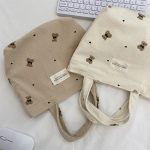 Detailed close-up of corduroy tote bags featuring cute bear embroidery and textures