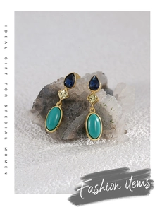 Detailed view of teardrop blue zircon and turquoise earrings on a crystal stone background