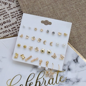 Detail of 16-pair gold earring set featuring butterflies, pearls, and dream letters