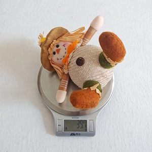 Close-up showing a 39.7g Thanksgiving scarecrow plush doll on a kitchen scale