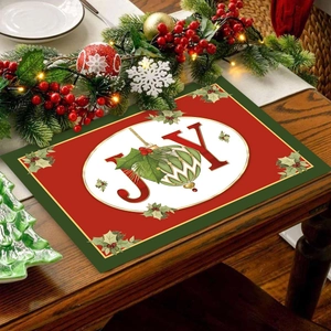Christmas JOY placemat with red and green festive decor on a wooden dining table
