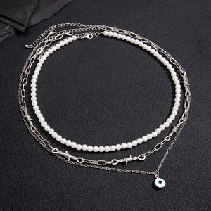 Three-layer layered necklace featuring white pearls, thorn chain, and blue evil eye pendant