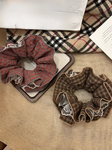 Detail of red and brown plaid scrunchies with elegant white lace trim and cotton texture