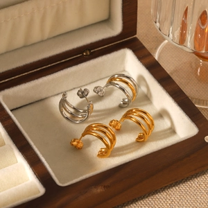 Three-layered 18k gold and silver stainless steel stud earrings in a wooden jewelry box