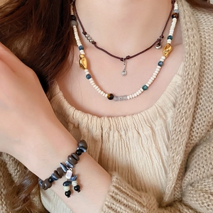 Detail shot of layered acrylic coffee bean beaded necklaces and fú character bracelet
